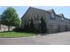 Side view of a well-maintained townhome, featuring a garage, green grass, and mature trees at 569 Alton Way # E, Denver, CO 80230