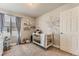 Bright Bedroom with a crib, plush toys and wall decals, creating a cozy and inviting space at 16057 E 47Th Pl, Denver, CO 80239
