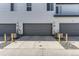 Close-up of townhome garages with individual doors and unit numbers, plus yellow bollards at 16057 E 47Th Pl, Denver, CO 80239