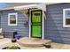 Close-up of a vibrant green front door with a protective awning and potted plants at 1995 Xenia St, Denver, CO 80220
