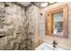 Rustic bathroom with stone-tile shower, wood-paneled walls, and modern vanity at 451 W 152Nd Ave, Broomfield, CO 80023