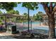 Community pool surrounded by mature trees, patio furniture, and a black metal fence at 804 Summer Hawk Dr # 3202, Longmont, CO 80504