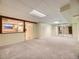 Finished basement with neutral carpet, bright lighting, and partial kitchen view at 5721 Everett St, Arvada, CO 80002