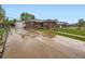 View of the brick house with a long driveway, detached garage, and fenced yard at 5721 Everett St, Arvada, CO 80002