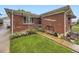 Close up of a brick home's front exterior with landscaped yard and awning covered window at 5721 Everett St, Arvada, CO 80002
