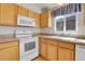Kitchen featuring modern white appliances, wood cabinets, and tile countertops at 6295 Clayton Cir, Frederick, CO 80530