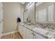 Light-filled bathroom with dual sink vanity with granite countertop, wood-look floors, and updated lighting at 12344 Turquoise Terrace St, Castle Pines, CO 80108