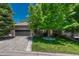 Well-kept brick home featuring an attached two-car garage and mature trees on a lush green lawn at 12344 Turquoise Terrace St, Castle Pines, CO 80108