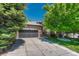 Beautiful brick home with a well-manicured lawn, mature trees, and a spacious two-car garage at 12344 Turquoise Terrace St, Castle Pines, CO 80108