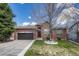 Charming brick home featuring a well-manicured lawn, dark garage door, and classic architectural details at 12344 Turquoise Terrace St, Castle Pines, CO 80108