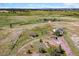 Aerial view of a spacious home and barn with fenced areas, outbuildings, and picturesque pastures at 40121 County Road 21, Elizabeth, CO 80107