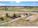 Overhead view of a home, barn, corrals, and outbuildings set amongst rolling pastures and mature trees on a sprawling property at 40121 County Road 21, Elizabeth, CO 80107