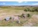 Expansive aerial view of the property with a house, barn, outbuildings, fences, and rolling fields at 40121 County Road 21, Elizabeth, CO 80107