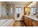 A full bathroom featuring double sinks, wooden cabinetry, and a glass shower, tiled floors, and a window at 40121 County Road 21, Elizabeth, CO 80107