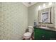 Stylish powder room with green vanity and patterned wallpaper at 6482 E Costilla Pl, Centennial, CO 80112