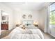 Sunlit bedroom featuring plush bedding, decorative pillows, side tables and view into the bathroom at 8571 Gold Peak Dr # F, Highlands Ranch, CO 80130