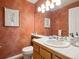 Bathroom featuring an interesting orange wall, a decorative mirror, and elegant fixtures at 8766 Cresthill Ln, Highlands Ranch, CO 80130