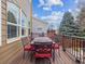 Deck with dining table, chairs with red cushions and wood railing that overlooks the yard at 8766 Cresthill Ln, Highlands Ranch, CO 80130