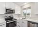 Bright kitchen includes stainless steel appliances, white cabinets, and a sink with a window view at 3667 W Union Ave # 2E, Denver, CO 80236