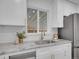 Close-up of a kitchen sink with granite countertops, stainless appliances, and white cabinetry at 7126 Joan St, Denver, CO 80221