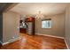 Dining area featuring modern chandelier, wood floors, and view into the updated kitchen at 13778 W 71St Pl, Arvada, CO 80004