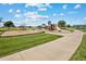 Community playground featuring swings, slides, and climbing structures, surrounded by lush green grass and walking paths at 2154 Alyssa St, Fort Lupton, CO 80621