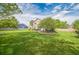 Expansive backyard with lush green grass, mature trees, and a cozy patio seating area at 4814 Kingbird Dr, Frederick, CO 80504