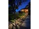 Beautifully landscaped front yard with a stone pathway and stylish lighting, creating a welcoming ambiance at night at 4814 Kingbird Dr, Frederick, CO 80504