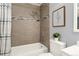 Bathroom featuring tile surround, shower head, tub, framed art, and a toilet at 9195 E Lehigh Ave # 190, Denver, CO 80237