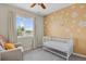 Cheerful Bedroom with a daisy-themed accent wall, a white crib, and a comfortable armchair at 20356 Willowbend Ln, Parker, CO 80138