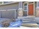 Front entrance with stone pillars, a red door and a gray garage door at 10206 Sedalia St, Commerce City, CO 80022