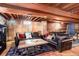 Finished basement with comfortable leather sofas, decorative rug and brick accents creating a cozy living space at 5332 W Roxbury Pl, Littleton, CO 80128