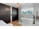 Bright bathroom with free standing tub, closet with mirrored door, hardwood floors, and stylish fixtures at 5332 W Roxbury Pl, Littleton, CO 80128