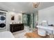 Bright bathroom with a glass enclosed shower, vanity, and stackable washer and dryer behind a sliding barn door at 5332 W Roxbury Pl, Littleton, CO 80128