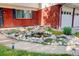 Charming front yard water feature surrounded by decorative rocks and lush plants by the brick house and two-car garage at 5332 W Roxbury Pl, Littleton, CO 80128