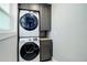 Convenient laundry area with a stacked washer and dryer set, and gray cabinetry in a well-lit space at 5332 W Roxbury Pl, Littleton, CO 80128