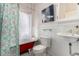 Charming bathroom featuring a red clawfoot tub, modern toilet, and pedestal sink at 2664 Dahlia St, Denver, CO 80207