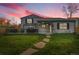 Beautiful backyard at dusk with large grassy area, deck, and privacy fence at 4924 S Flower Way, Littleton, CO 80123