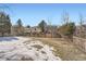 Fenced backyard with a mix of grass and snow, surrounded by trees, providing a private and serene outdoor space at 9383 Cobblecrest Dr, Highlands Ranch, CO 80126