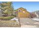 Charming mustard home featuring a two-car garage and well-maintained front yard with green grass and stone details at 9383 Cobblecrest Dr, Highlands Ranch, CO 80126