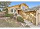 Mustard-colored home exterior with a red front door, stone accents, and neatly manicured landscaping at 9383 Cobblecrest Dr, Highlands Ranch, CO 80126