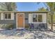 A gray home front porch area, enhanced with seating and a vibrant orange door at 5330 S Windermere St, Littleton, CO 80120