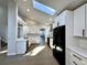 Bright kitchen with white cabinetry, quartz countertops, and modern black appliances beneath a skylight at 9668 Salem Ct, Highlands Ranch, CO 80130