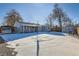 Large snow covered backyard featuring a carport, a shed, patio and the back side of the house at 2701 S Knox Ct, Denver, CO 80236