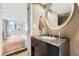 Bathroom sink featuring a round mirror and open view into a bedroom at 2701 S Knox Ct, Denver, CO 80236