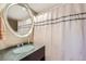 Bathroom with shower curtain, large round mirror over the sink, and neutral color scheme at 2701 S Knox Ct, Denver, CO 80236