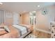 Bright bedroom with wood floors, light walls, decorative wall art, and a view into the hallway at 2701 S Knox Ct, Denver, CO 80236