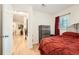 Bedroom with wood floors, closet, and a comfortable bed with red bedding and view to entry hall at 2701 S Knox Ct, Denver, CO 80236