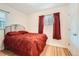 Bedroom featuring wood floors, window, and a comfortable bed with red bedding at 2701 S Knox Ct, Denver, CO 80236