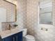 Stylish half bathroom featuring designer wallpaper, blue vanity, and gold fixtures at 5755 Boston St, Denver, CO 80238